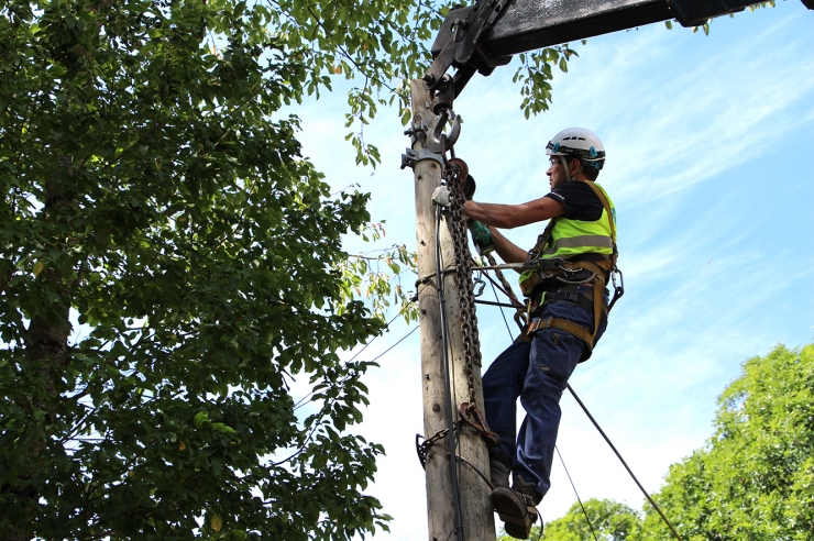 Un operari tallant els cables de la línia aèria.