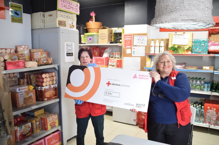 Dues col·laboradores de la botiga solidària amb el xec de la campanya d'Andorra Telecom i Bomosa.
