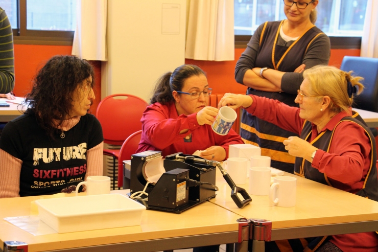 Estampació d'un dibuix en unes tasses, a càrrec d'usuaris de Xeridell, taller ocupacional per a persones amb discapacitat.