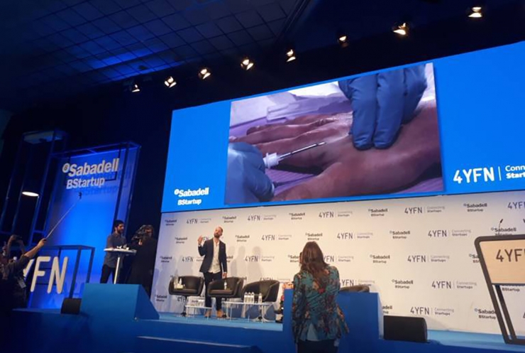 La pantalla gegant mostra el moment en què l'emprenedor s'implanta el xip.