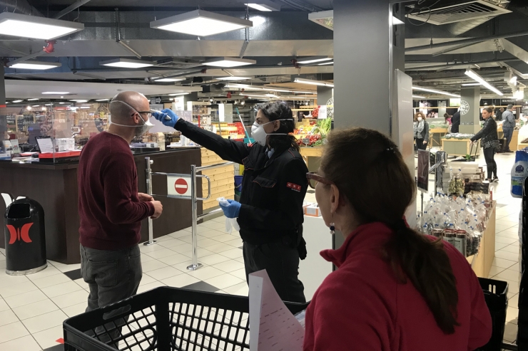 Personal de Pyrénées pren la temperatura a un client abans d’accedir al supermercat.