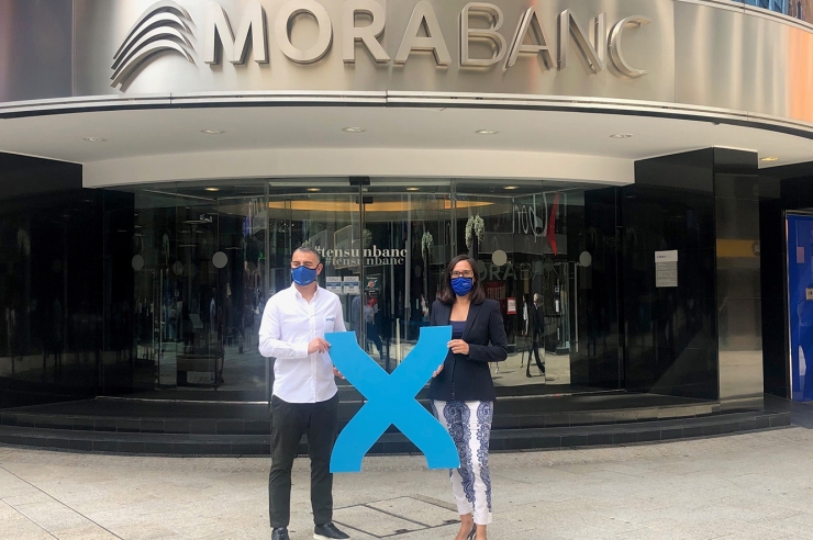 La directora de banca país de MoraBanc, Marta Riera, i David Ledesma, director de màrqueting de Grandvalira, al davant de la seu social de l'entitat bancària.