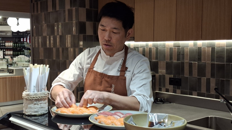 Un cuiner preparant el sushi.