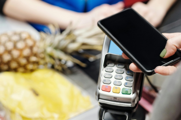 Una noia pagant una compra amb el seu telèfon mòbil.